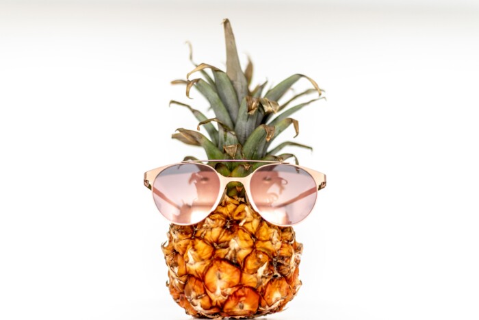 Ananas die eine Sonnenbrille trägt vor weißem Hintergrund